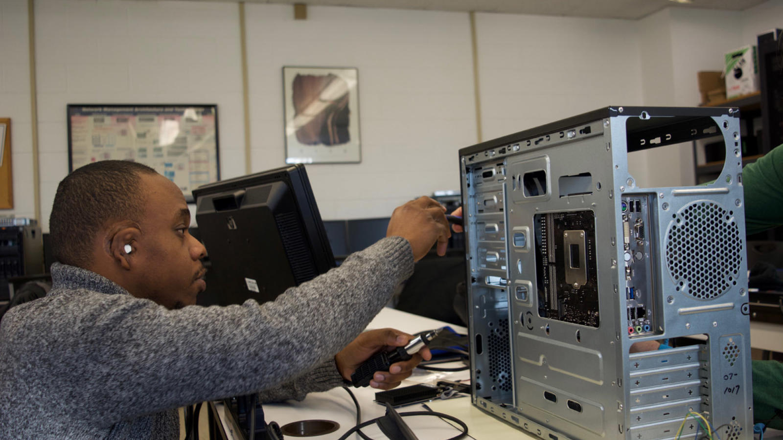 A CNST student troubleshoots a desktop tower system.