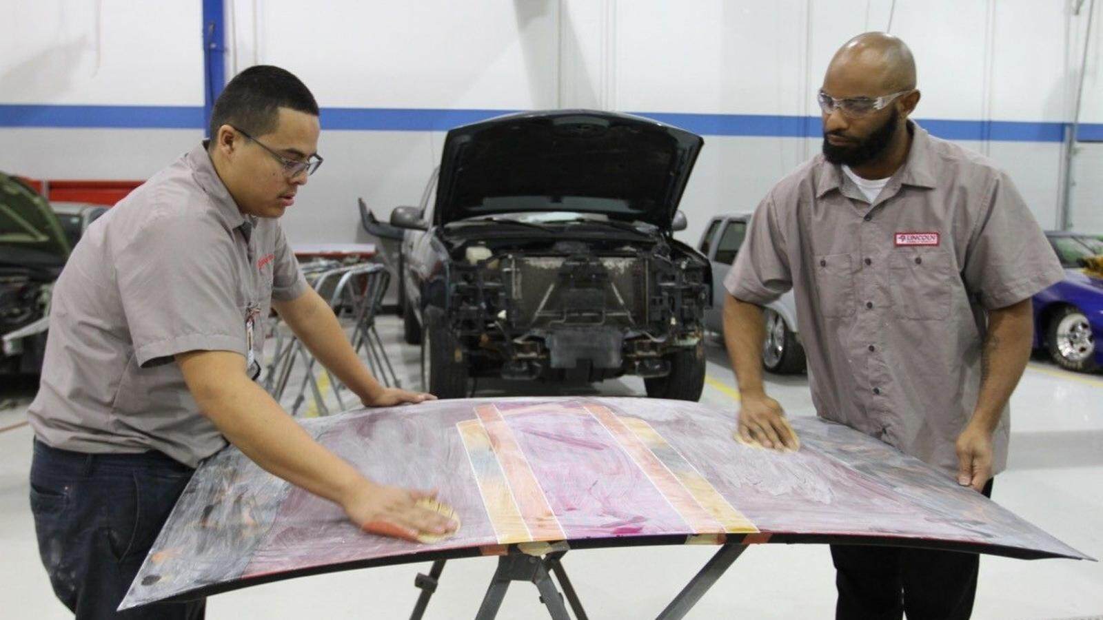 Collision repair students practice preparing a vehicles hood for final refinishing.