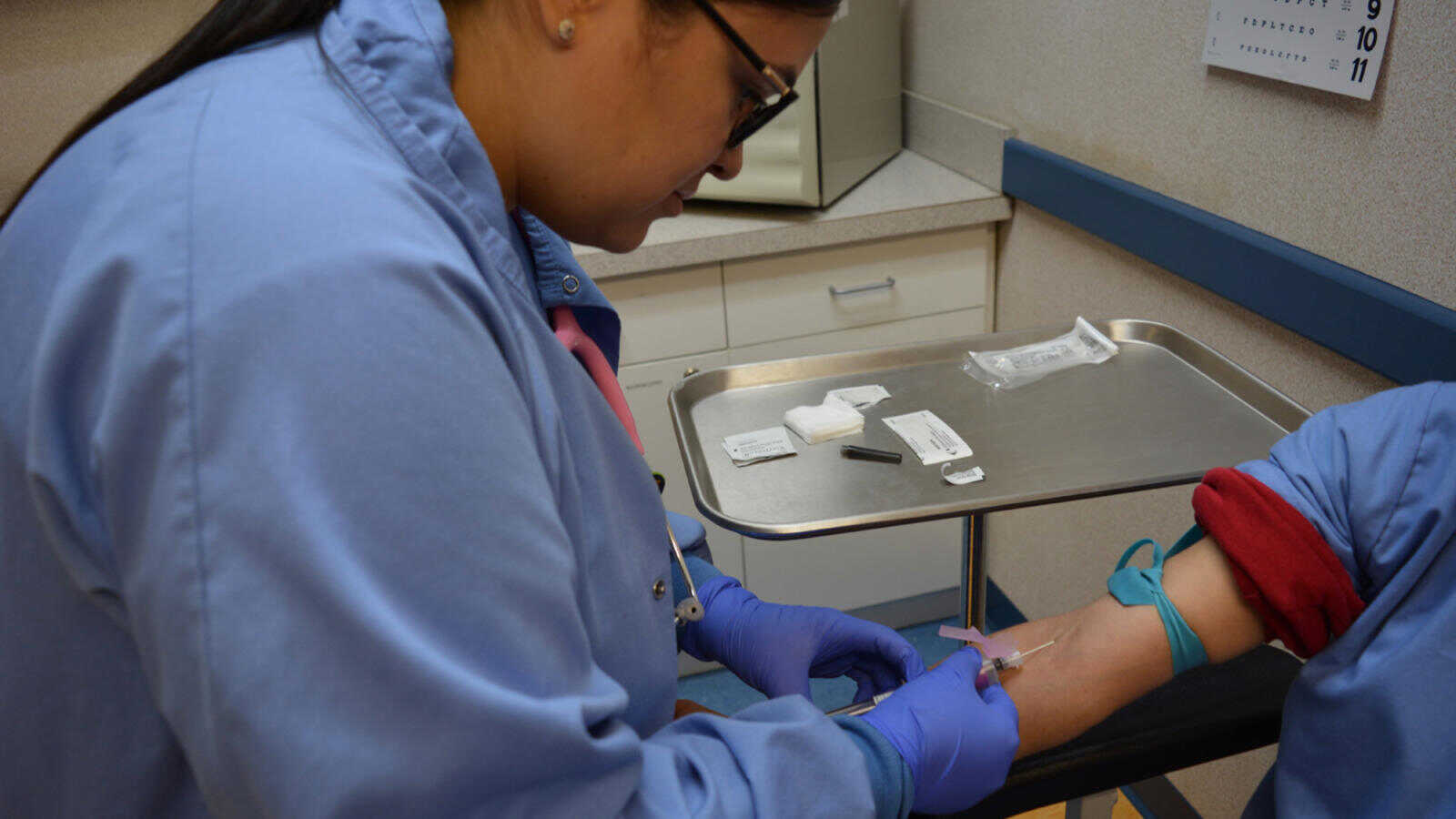 A medical assistant students practices drawing a blood specimen for testing