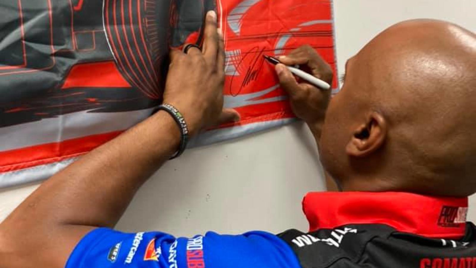 NHRA 3-Time World Champion Antron Brown autographs a racing banner at Lincoln Tech in East Windsor CT.