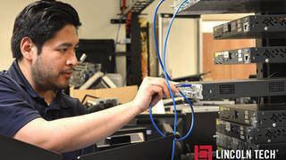 An information technology student sets up a server rack system