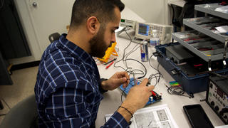 An electronics tech trainee at the Allentown campus tests a circuit board.